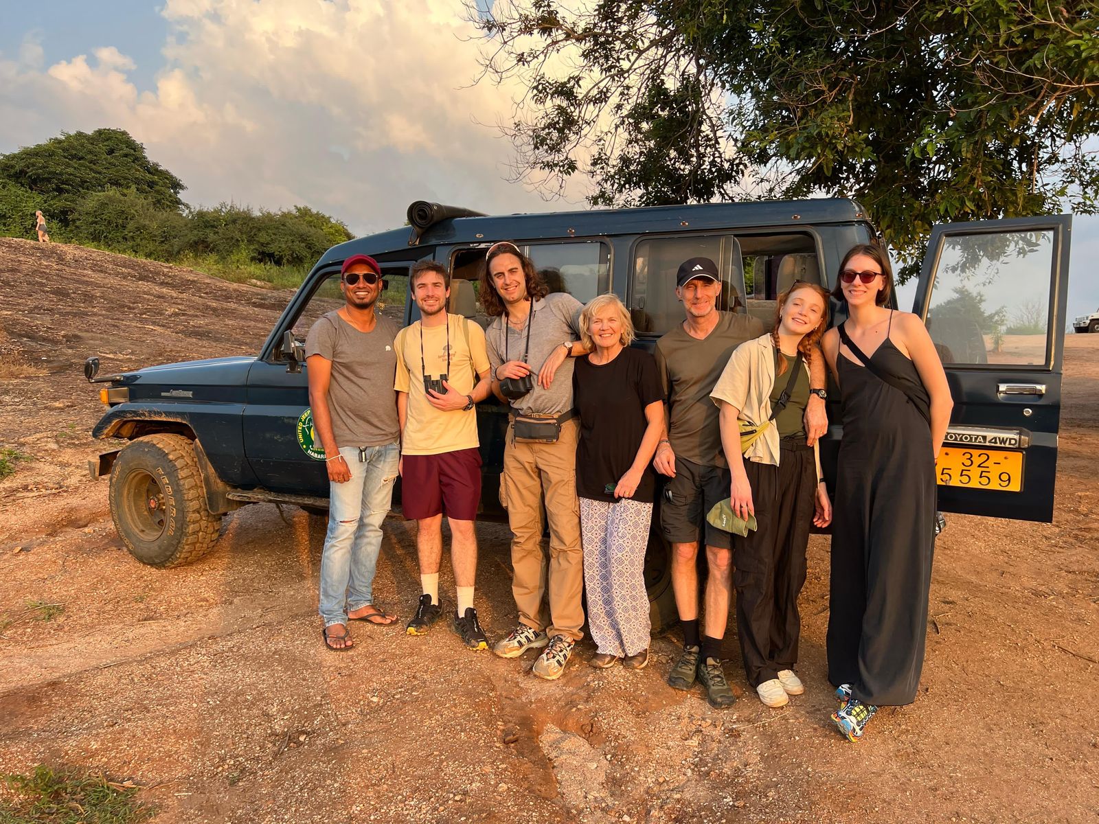 Ceylon Now driver-guide and six guests in front of a blue safari jeep after a game drive in Sri Lanka